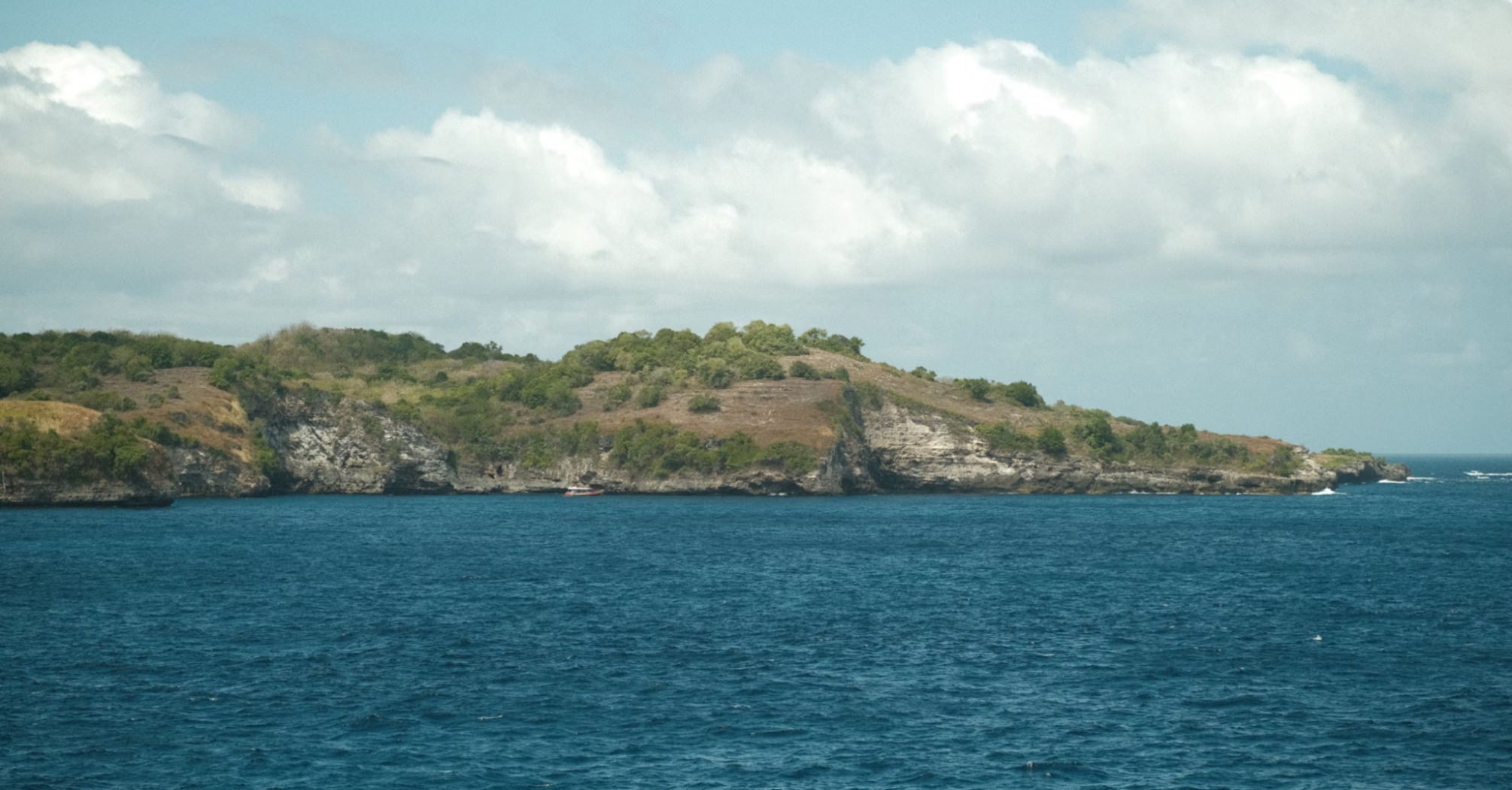 Rocky shoreline of a small uninhabited island with sparse vegetation and steep coastal cliffs