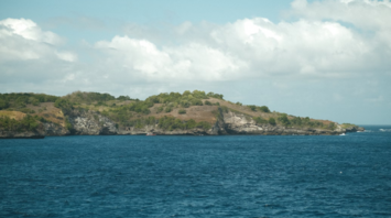 Rocky shoreline of a small uninhabited island with sparse vegetation and steep coastal cliffs