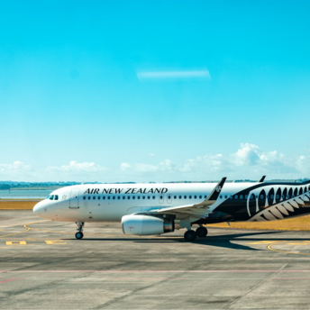 A parked Air New Zealand aircraft on the tarmac under a clear blue sky