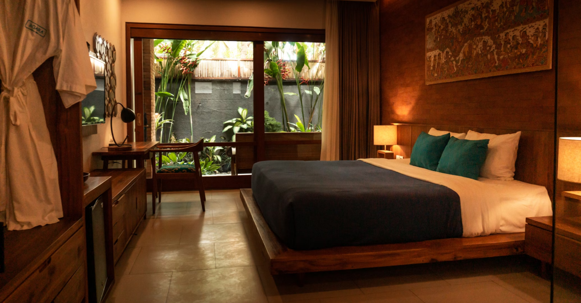 Hotel room with wooden interior, double bed, and garden view through glass doors