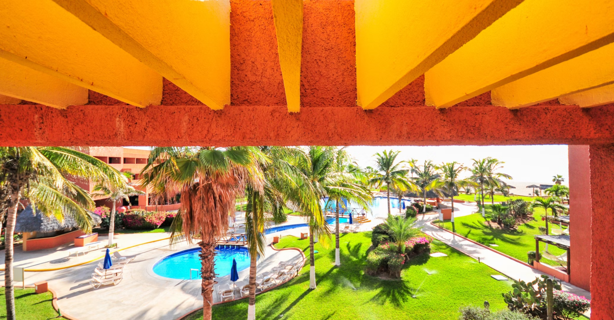 View of a tropical resort with palm trees, swimming pools, and colorful architecture