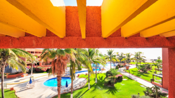 View of a tropical resort with palm trees, swimming pools, and colorful architecture