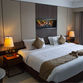 Modern hotel room with king-size bed, warm lighting, and fireplace-style wall feature