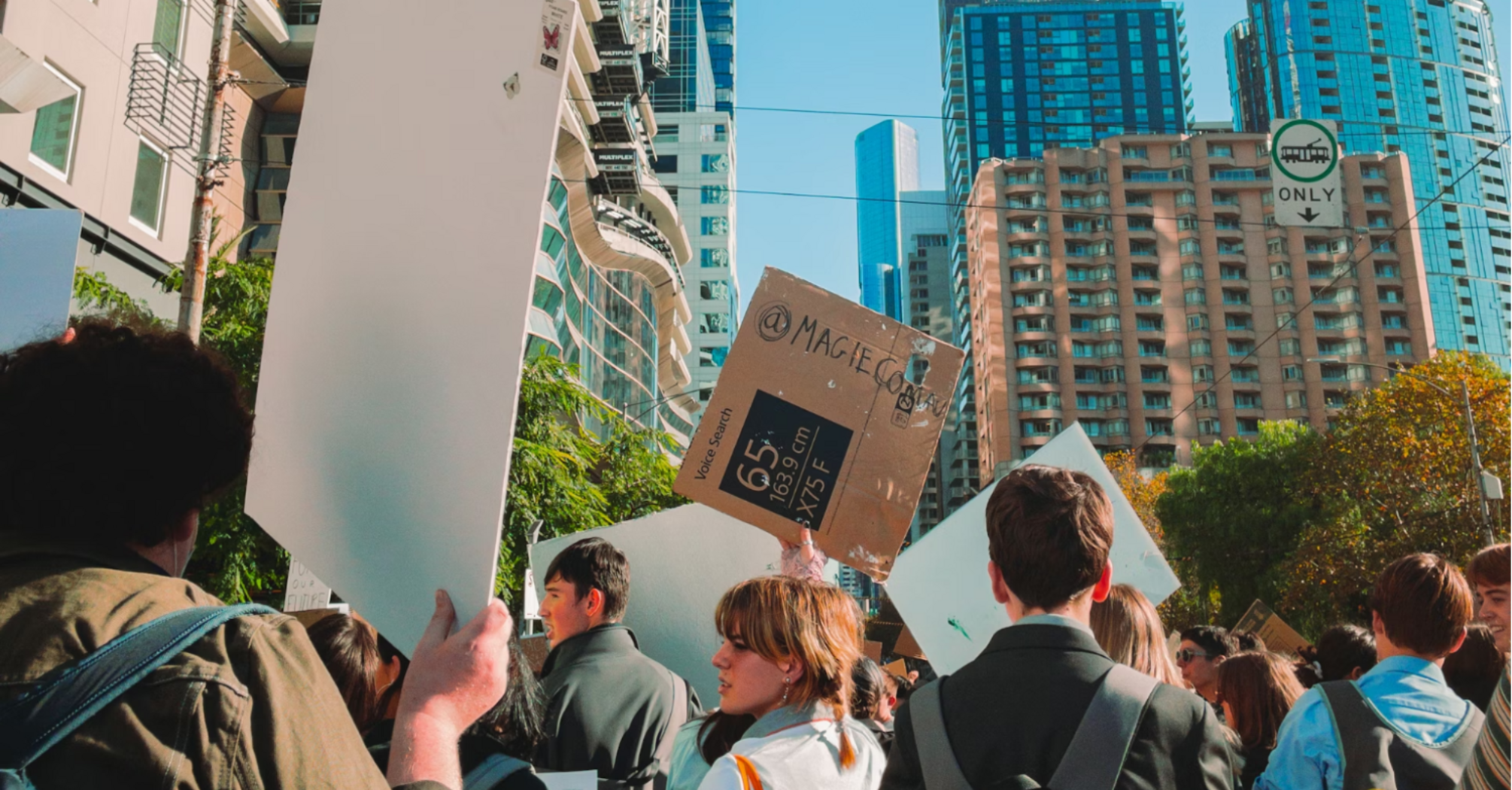 People holding protest signs during a city demonstration on a clear day