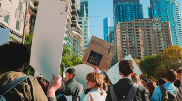 People holding protest signs during a city demonstration on a clear day