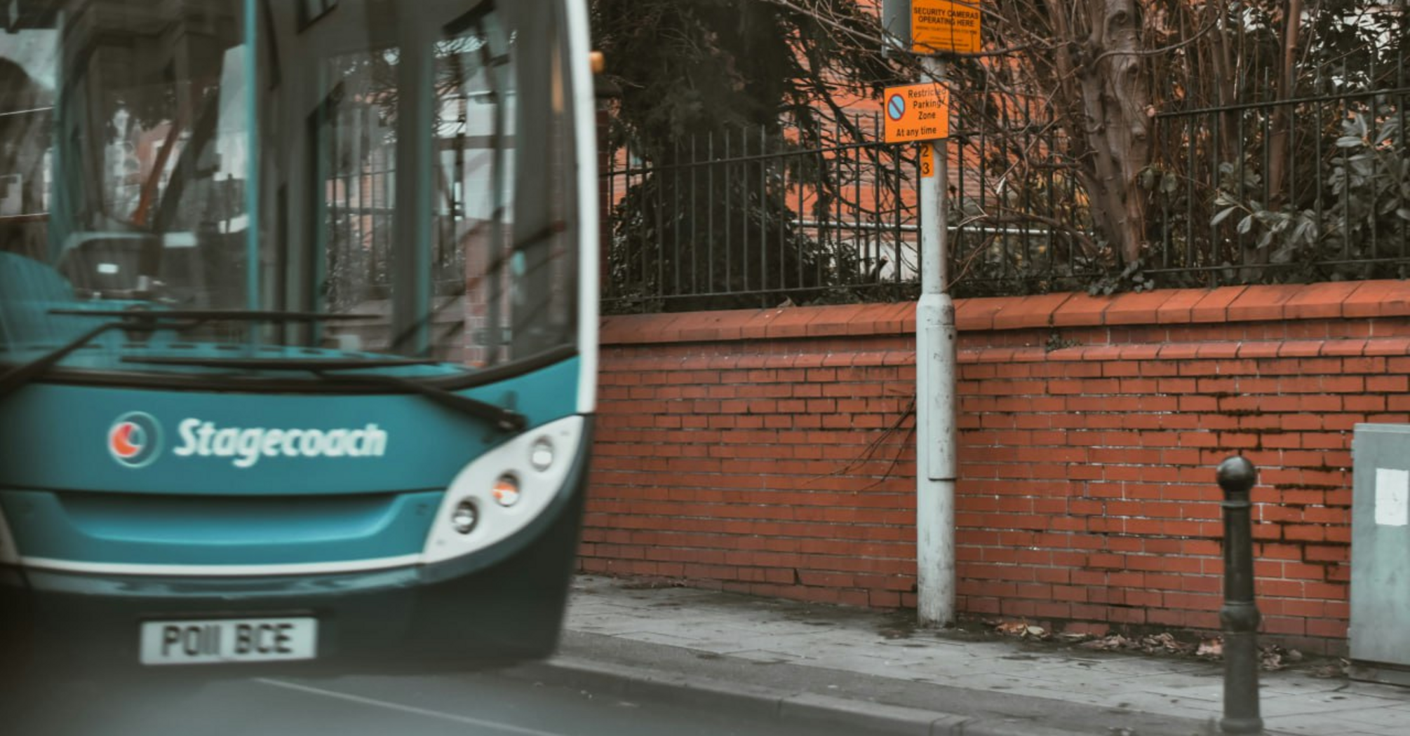 A Stagecoach bus on an urban street near a restricted parking zone and security camera sign