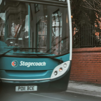 A Stagecoach bus on an urban street near a restricted parking zone and security camera sign