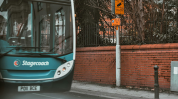 A Stagecoach bus on an urban street near a restricted parking zone and security camera sign