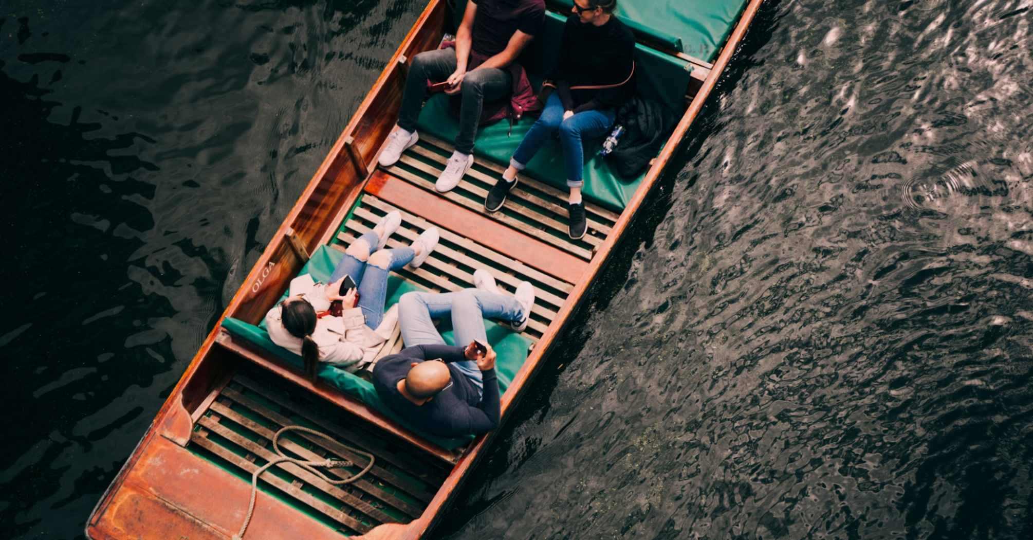 Group of people relaxing in a wooden boat on a calm lake