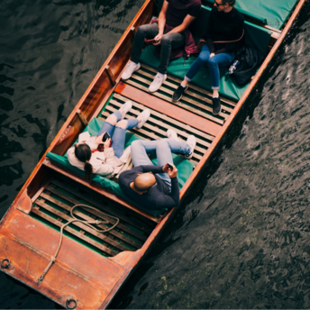 Group of people relaxing in a wooden boat on a calm lake