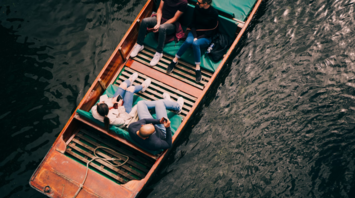 Group of people relaxing in a wooden boat on a calm lake