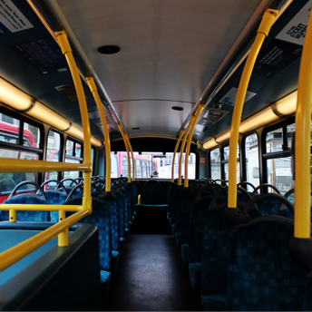 Interior of a city bus with empty seats and yellow handrails