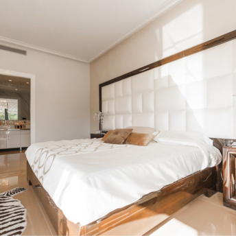 Bright and elegant hotel room with a large bed, modern decor, and natural sunlight