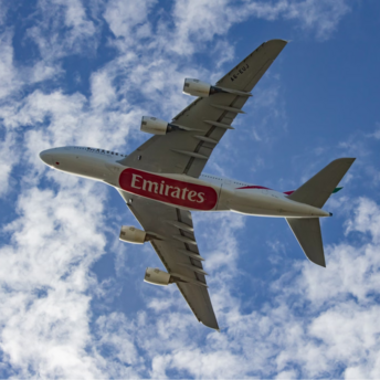 Emirates airplane flying through a partly cloudy sky