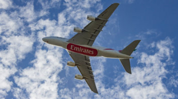 Emirates airplane flying through a partly cloudy sky