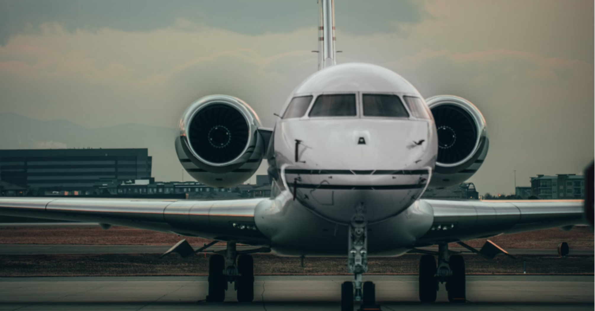 Front view of a small passenger jet on a runway during sunset