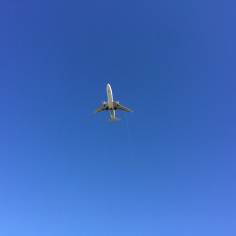 Airplane flying overhead against a clear blue sky