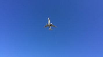 Airplane flying overhead against a clear blue sky