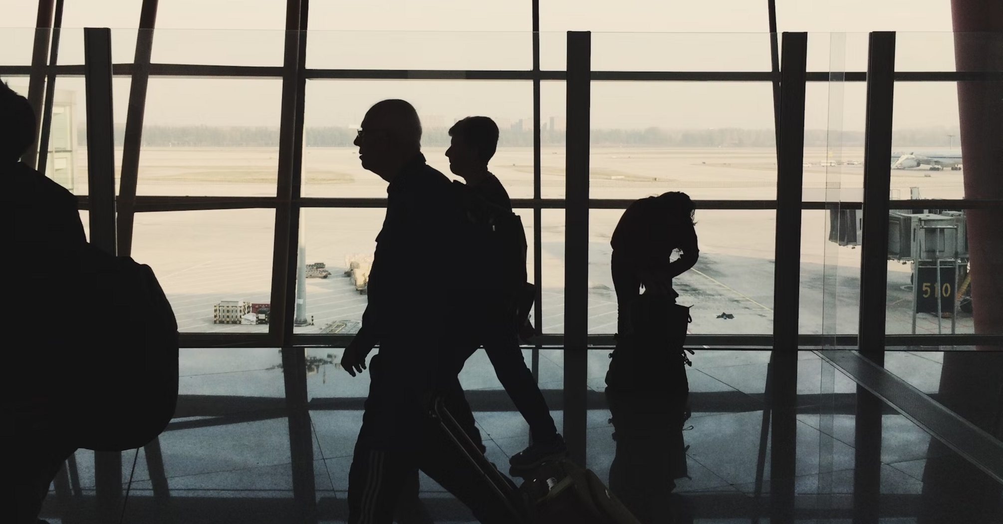 Silhouettes of passengers walking through an airport terminal