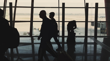 Silhouettes of passengers walking through an airport terminal