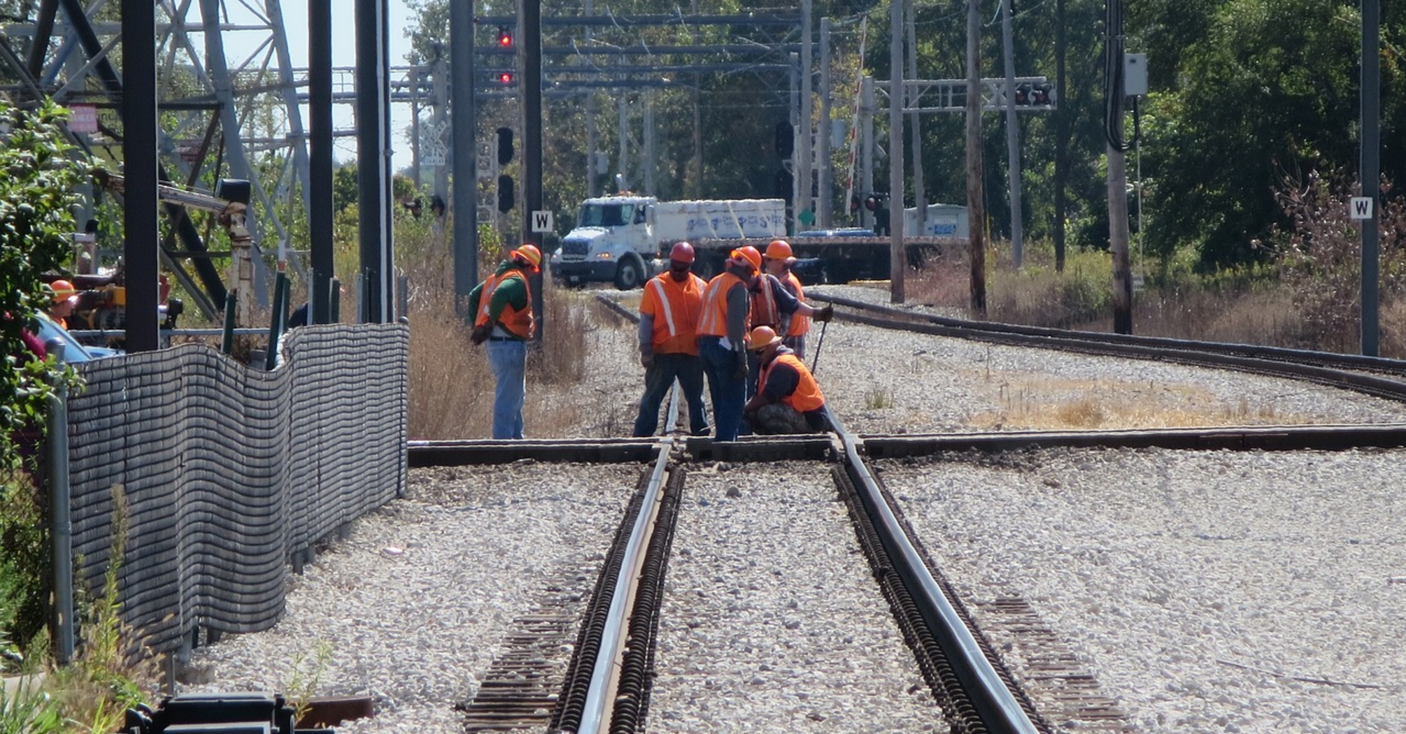 Rail workers performing maintenance on a track under sunny conditions