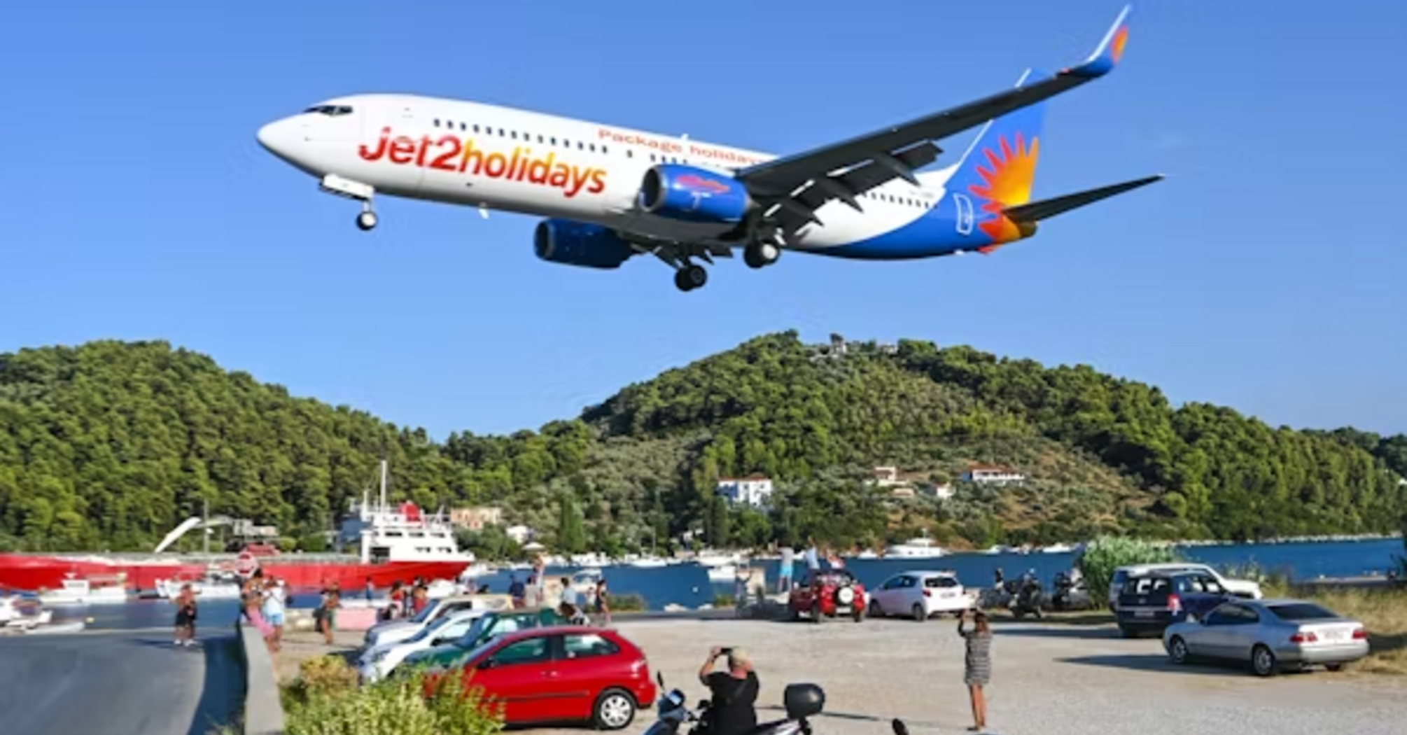 A large passenger jet flying over lush green hills, symbolizing travel with Jet2holidays