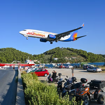 A large passenger jet flying over lush green hills, symbolizing travel with Jet2holidays