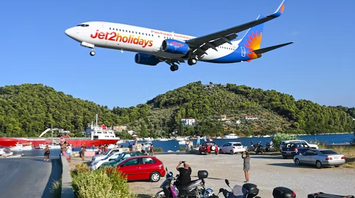 A large passenger jet flying over lush green hills, symbolizing travel with Jet2holidays