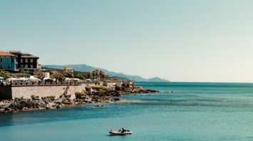 View of Alghero coastline with small boat in turquoise water