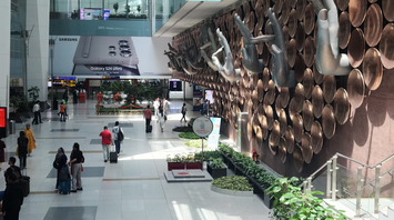 Indira Gandhi International Airport terminal in New Delhi with travelers and artistic mudra hand installation on the wall