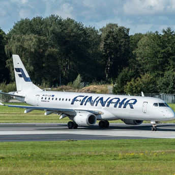 Finnair aircraft taxiing on a runway surrounded by trees