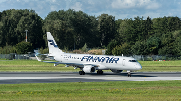 Finnair aircraft taxiing on a runway surrounded by trees