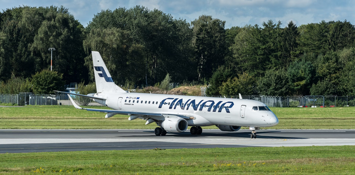 Finnair aircraft taxiing on a runway surrounded by trees