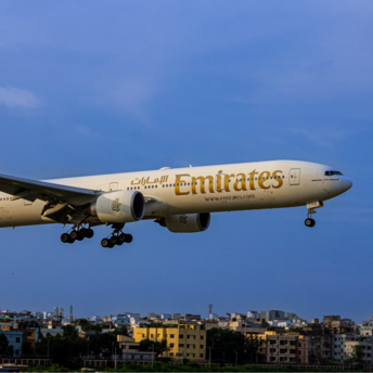 Emirates aircraft approaching landing with cityscape below