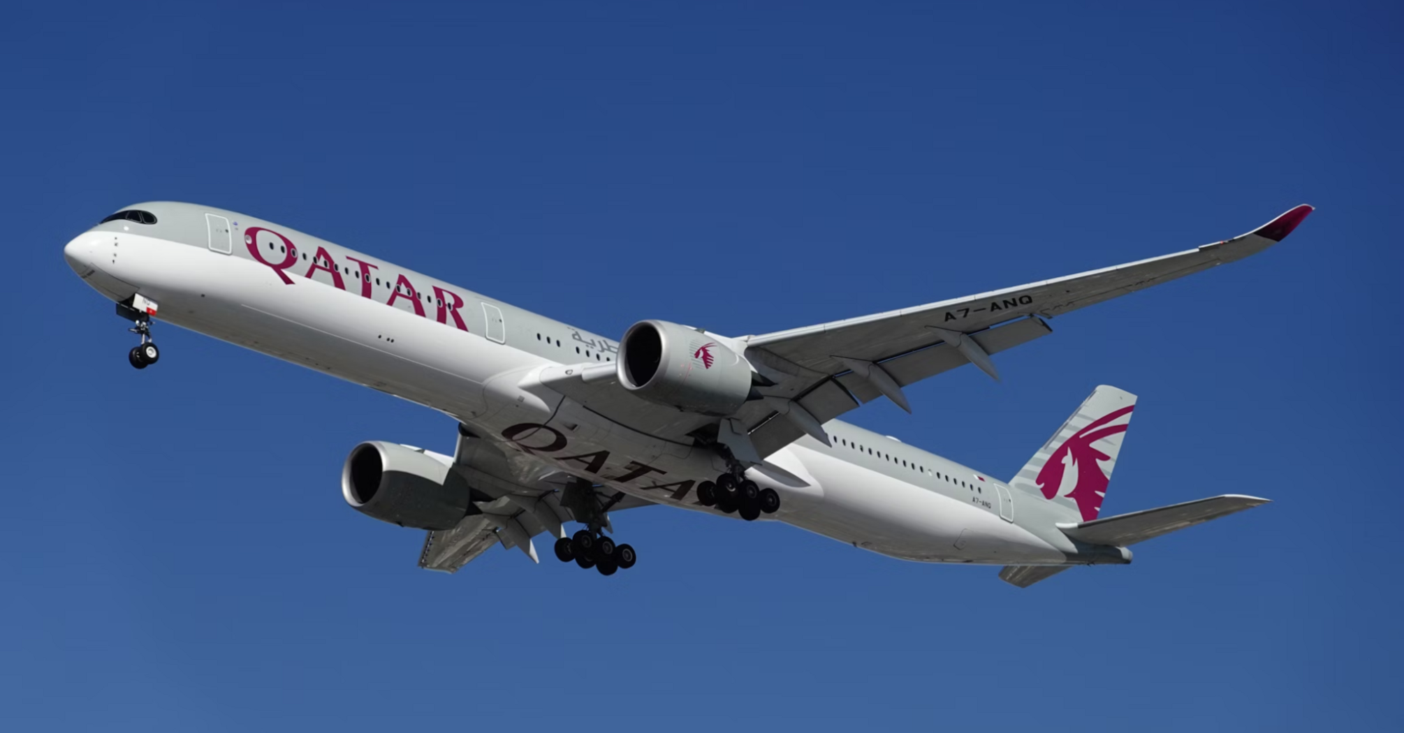 Qatar Airways aircraft in flight against a clear blue sky