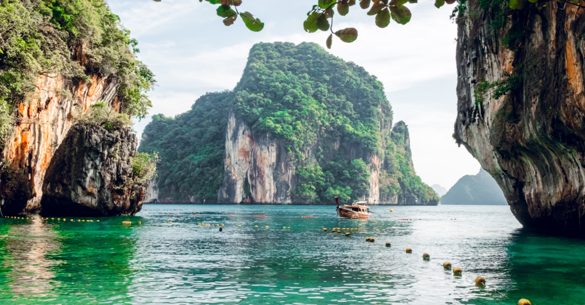 Scenic view of a traditional boat near limestone cliffs and clear green water in Krabi