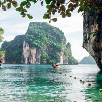 Scenic view of a traditional boat near limestone cliffs and clear green water in Krabi