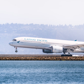 Cathay Pacific airplane on runway near water, preparing for takeoff