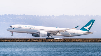 Cathay Pacific airplane on runway near water, preparing for takeoff