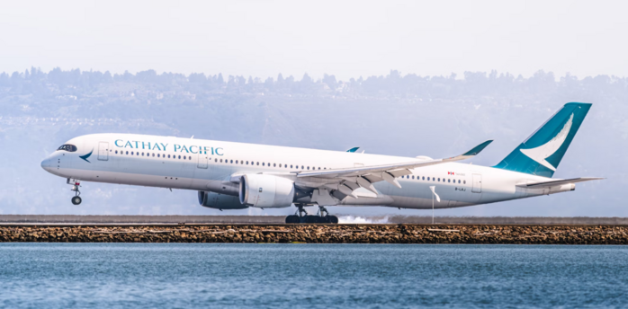 Cathay Pacific airplane on runway near water, preparing for takeoff