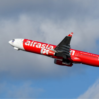 AirAsia aircraft in flight against a cloudy sky