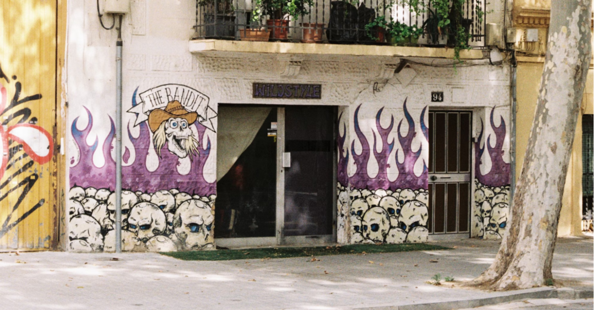 Residential building in Poblenou with graffiti on the ground floor and plants on balconies