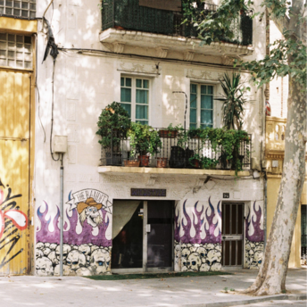 Residential building in Poblenou with graffiti on the ground floor and plants on balconies