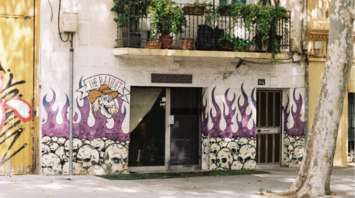 Residential building in Poblenou with graffiti on the ground floor and plants on balconies