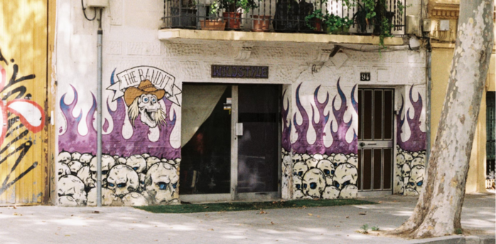 Residential building in Poblenou with graffiti on the ground floor and plants on balconies