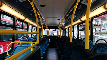 Empty interior of a public bus with yellow poles and blue seats