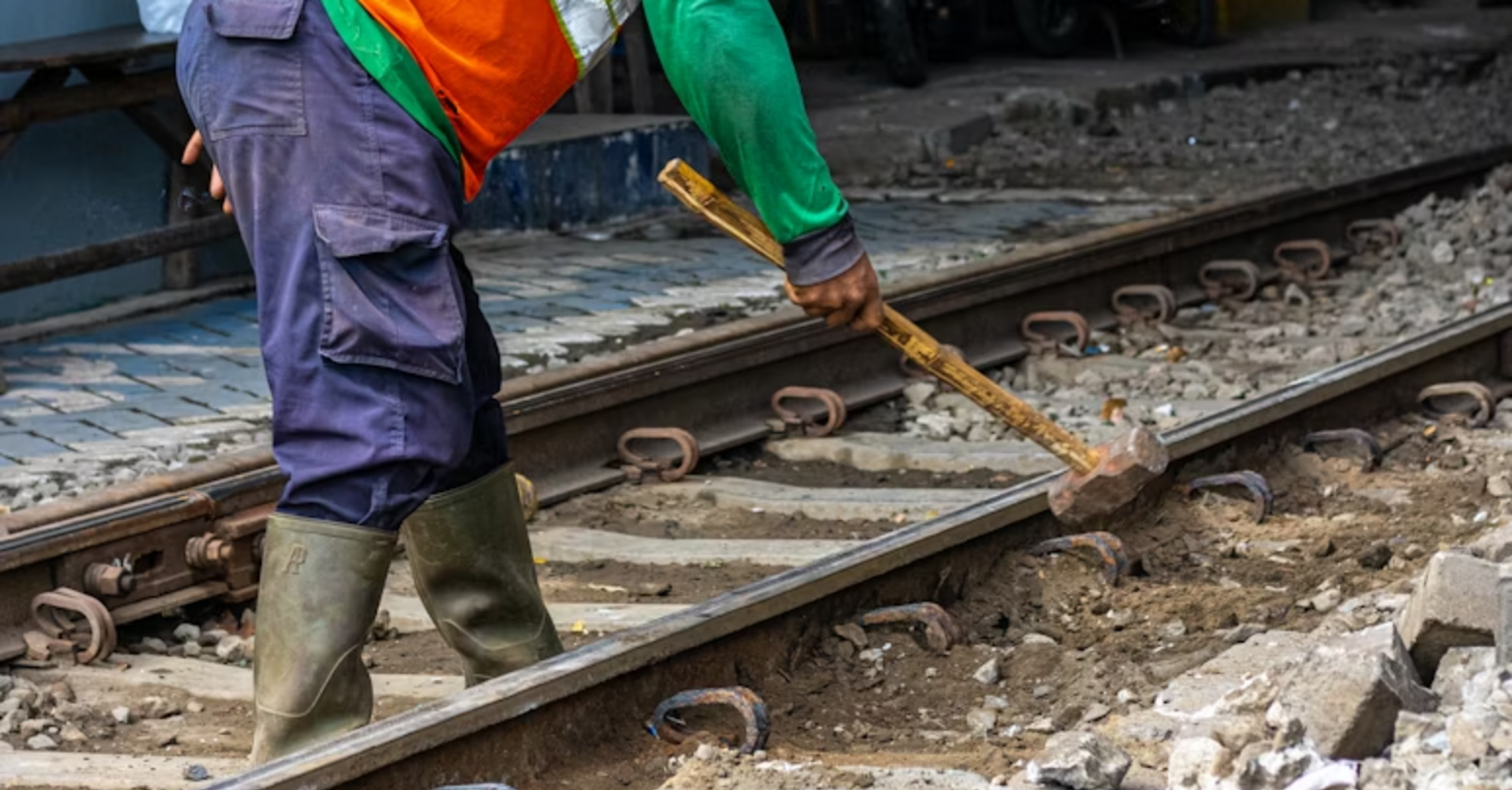 Railway worker carrying out track maintenance with hand tools