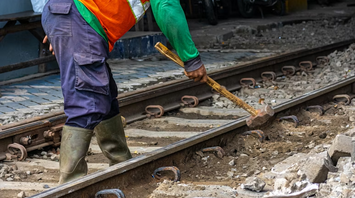 Railway worker carrying out track maintenance with hand tools