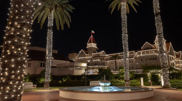 Night view of Hotel del Coronado with lit palm trees and fountain
