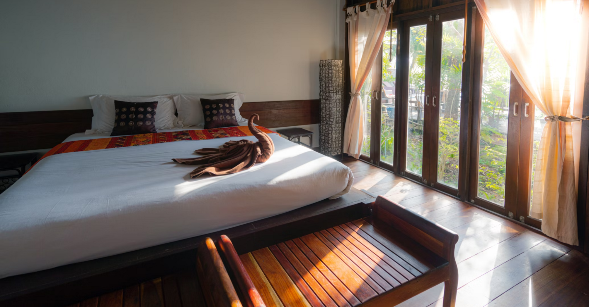 Modern hotel room with wooden interior and sunlight streaming through large windows